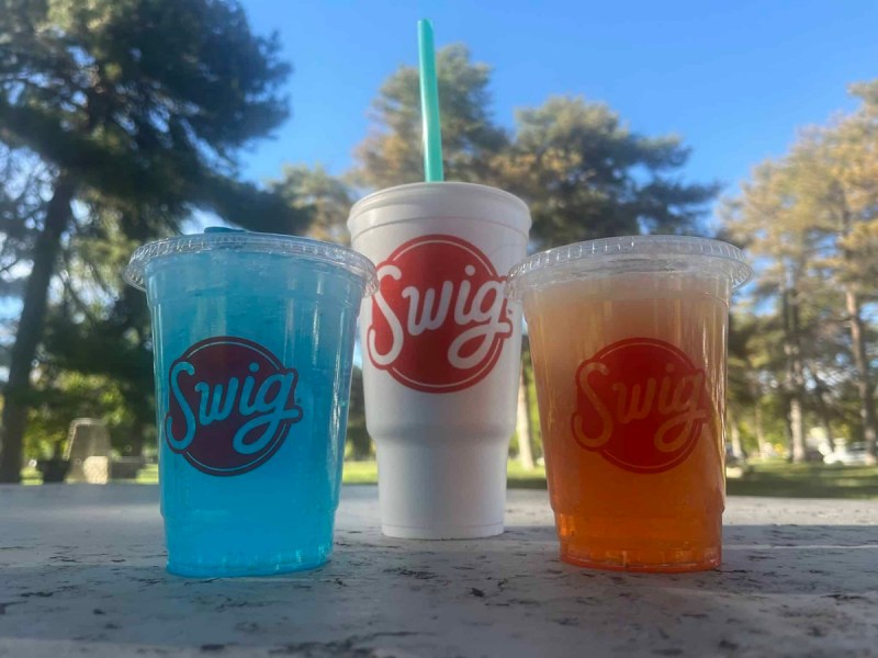 A slate of Swig drinks on a picnic table
