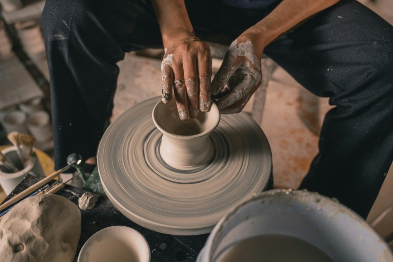 A potter throwing a clay pot on a pottery wheel.