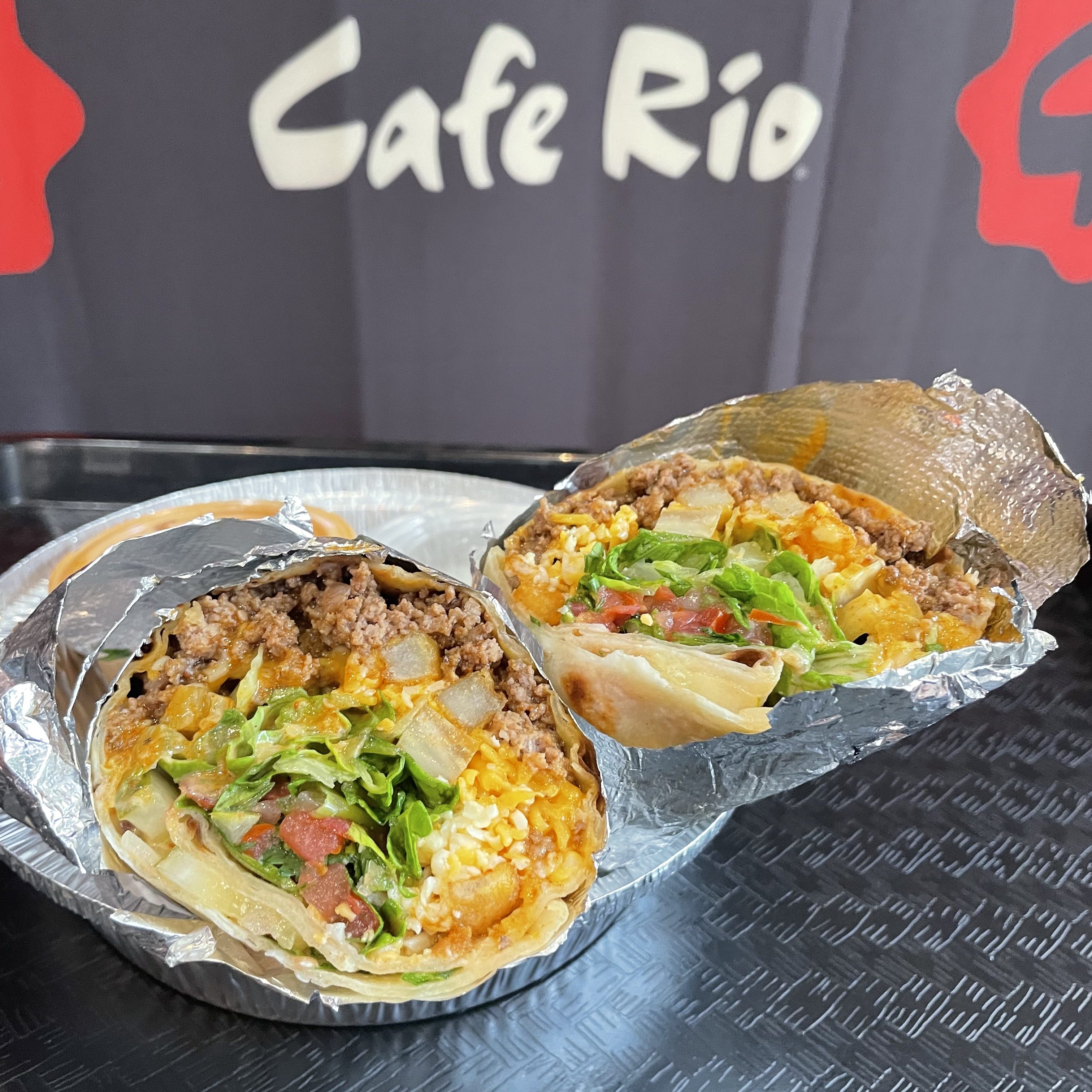 A cafe rio sign in the background highlights the black serving tray holding a burrito slide in half, filled to the brim.